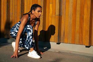 des sports fille sur une en bois mur Contexte en train de préparer à courir photo