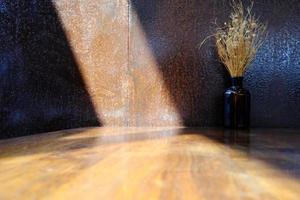 herbe fleur dans le bouteille, en mettant sur le en bois table avec lumière faisceau de le la fenêtre. photo