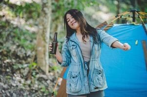 jeune femme applaudir et boire une boisson devant la tente de camping photo