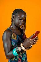 Jeune africain américain femelle avec traditionnel robe bavardage avec une téléphone intelligent photo