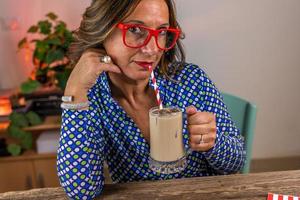 femme habillé dans bleu chemise séance en buvant du froid café par une paille photo