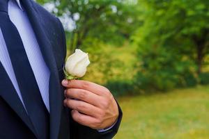 mariage. le jeune marié dans une chemise et gilet avec boutonnière est dans le jardin photo