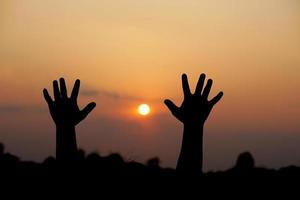 silhouette de Humain main élevé à faire une souhait, le coucher du soleil Contexte photo