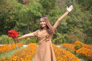 asiatique femme souriant Heureusement parmi magnifique fleurs photo