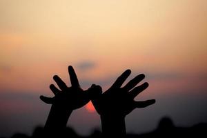 Humain main silhouette de en volant oiseau le coucher du soleil Contexte photo