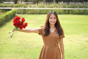 asiatique femme souriant Heureusement parmi magnifique fleurs photo