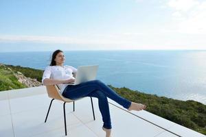 jeune femme détendue à la maison travaillant sur un ordinateur portable photo