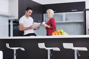 couple heureux lisant le journal dans la cuisine au petit déjeuner photo