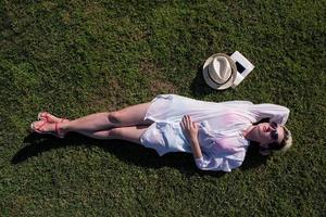 Haut vue de au dessus de une femme mensonge et relaxant sur une Prairie couvert avec vert herbe sur une ensoleillé été ou printemps journée. photo
