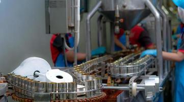 usine de conserves de poisson. industrie alimentaire. sardines à la sauce tomate rouge dans des boîtes en conserve à l'usine alimentaire. chaîne de production agro-alimentaire. l'industrie agroalimentaire. de nombreuses boîtes de sardines sur un tapis roulant. photo