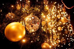 Noël arbre avec or Balle et bokeh lumières Contexte. Noël abstrait proche en haut avec embrasé décorations en plein air. photo