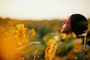 jolie jeune femme noire porte une robe d'été pose dans un champ de tournesol. photo