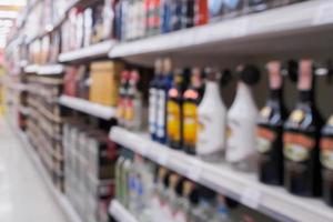 bouteilles d'alcool de vin et étagères de boissons alcoolisées dans un supermarché ou un magasin d'alcools arrière-plan flou photo