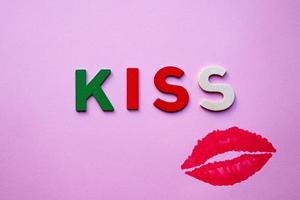 lèvres et mot de baiser avec des lettres en bois sur le fond rose photo