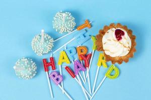 Gâteaux et petits gâteaux avec arc-en-ciel anniversaire bougies avec le mots content anniversaire. anniversaire fête. photo