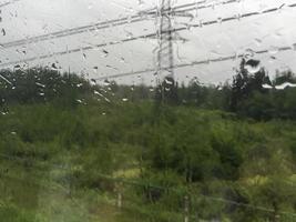 texture de une fenêtre avec gouttes de pluie. surplombant une rural paysage. photo