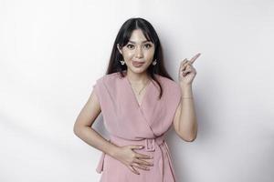 affamé asiatique femme habillé dans rose, montrer du doigt à le copie espace sur Haut de son, isolé par blanc Contexte photo