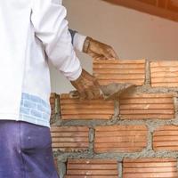 homme main avec truelle plâtrage une mur, parcourir enrobage plâtre des murs photo