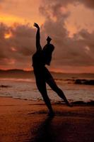 silhouette de un asiatique femme en jouant dans le l'eau sur le plage avec fort vagues s'écraser photo