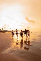 une groupe de asiatique adolescents fonctionnement avec content expressions sur vacances avec leur copains ivre sur le plage photo