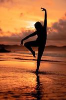 un indonésien femme dans silhouette Faire une magnifique Danse sur le plage avec le s'écraser vagues dans le après midi photo