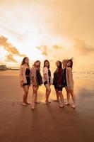 une groupe de asiatique femmes dans chemises posant Heureusement tandis que visite une magnifique plage photo