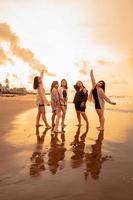 une groupe de asiatique femmes dans chemises posant Heureusement tandis que visite une magnifique plage photo