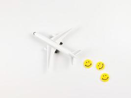 plat allonger de avion modèle avec Trois Jaune cercle souriant visages sur blanc Contexte. content ou amusement voyage concept. photo