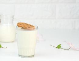 plein verre de Lait et une rond biscuit mouches dans le verre. blanc tableau, petit déjeuner photo