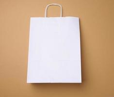 grand jetable blanc kraft papier sac avec poignées sur une marron arrière-plan, éco emballage photo