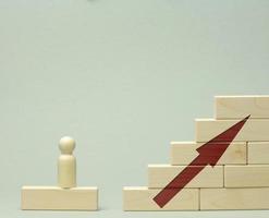 en bois figurine de une homme des stands sur une escalier fabriqué de blocs sur le premier marcher. le concept de réalisation le ensemble buts dans entreprise, carrière croissance photo