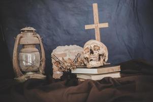 Nature morte avec des crânes sur des livres, de vieilles lampes, des fleurs sèches et des fusils croisés photo