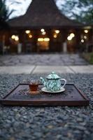une théière rempli avec chaud thé, le long de avec une verre, est prêt à être servi et apprécié dans le après-midi. photo