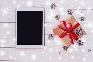 Haut vue tablette, et cadeau boîte avec neige, flocons de neige sur blanc bois Contexte pour Noël et Nouveau an. photo