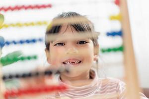 une jeune fille asiatique mignonne utilise le boulier avec des perles colorées pour apprendre à compter à la maison photo