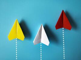 jaune, blanc et rouge papier avion origami courses à atteindre destination sur bleu Contexte avec personnalisable espace pour texte. affaires buts concept photo