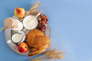 une argent plateau rempli avec une variété de traite pour le juif vacances de shavuot-lait des produits, pain, fruit et oreilles de maïs. Haut voir. une copie espace. photo