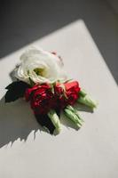gros plan sur les fleurs de la boutonnière du marié avec des roses blanches, du vert et de la verdure. notion de mariage. belles fleurs vivantes photo