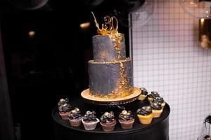 de fête à deux niveaux noir gâteau avec or décoration pour le 30 anniversaire. beaucoup Chocolat et vanille petits gâteaux avec luxe décoration. candybar pour anniversaire photo