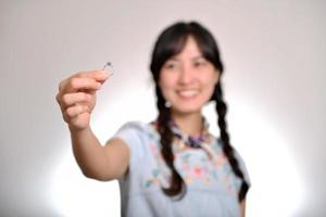 portrait de la belle jeune femme asiatique en robe denim tenant une bague de fiançailles sur fond blanc photo