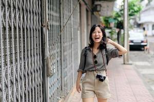 Jeune asiatique femme sac à dos voyageur profiter rue culturel local endroit et sourire. voyageur vérification en dehors côté des rues. photo