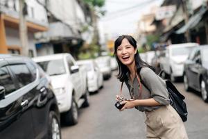 Jeune asiatique femme sac à dos voyageur en utilisant numérique compact caméra, profiter rue culturel local endroit et sourire. photo