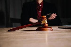 concept de justice et de droit. juge masculin dans une salle d'audience avec le marteau, travaillant avec, clavier d'ordinateur et d'accueil, lunettes, sur table à la lumière du matin photo