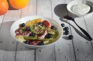 photo encore vie, assiette avec fruit salade, myrtille baies, cuillère et yaourt , rustique