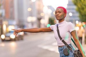 africain femme avec court rose cheveux coiffure saluer une Taxi photo