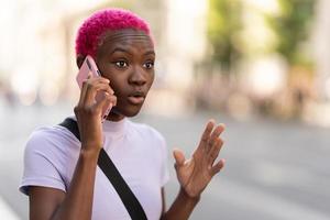 Jeune africain femme parlant énergiquement sur sa mobile en plein air photo