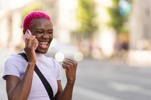 africain Jeune femme en riant tandis que parlant à le mobile en plein air photo