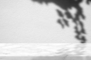 blanc marbre table avec pendaison feuilles ombre sur béton mur texture arrière-plan, adapté pour produit présentation toile de fond, afficher, et moquer en haut. photo