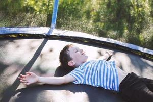 garçon sur le trampoline. le enfant mensonges sur une trampoline et repose photo