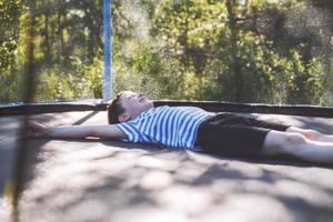 garçon sur le trampoline. le enfant mensonges sur une trampoline et repose photo